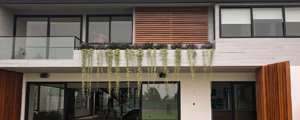Fachada de Casa Las Laderas con amplios ventanales, detalles en madera, balcones y vegetación integrada.