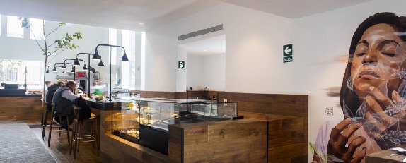 Interior de Cafe de Lima con mobiliario de madera, vitrinas de exhibición y espacios de atención al público.
