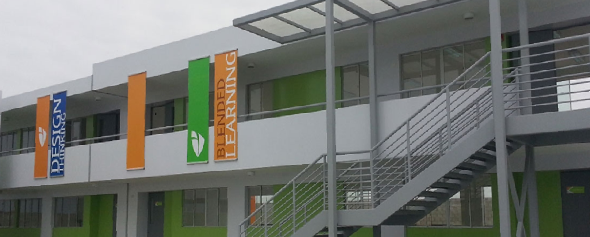 Fachada de Innova Schools con estructura moderna, escaleras exteriores y elementos gráficos en verde y naranja.