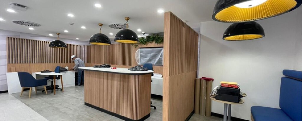 Interior de oficinas Interbank con recepción en madera, áreas de espera, iluminación moderna y espacios abiertos.