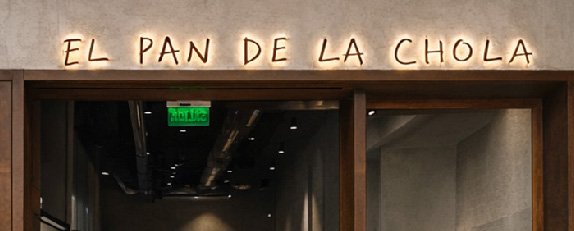 Interior de Pan de la Chola con acabados en madera, tonos neutros e iluminación cálida.