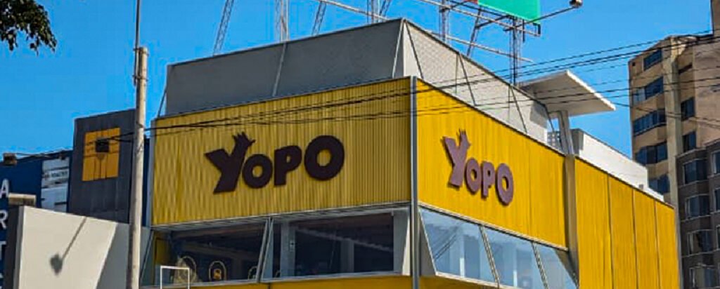 Fachada de Yopo con revestimiento amarillo, grandes ventanales y señalética de la marca.